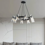 "A modern black brass chandelier with cone-shaped acrylic shades over a couch in a living room."