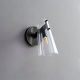 "A modern brass wall lamp with a clear acrylic shade on a gray textured wall."