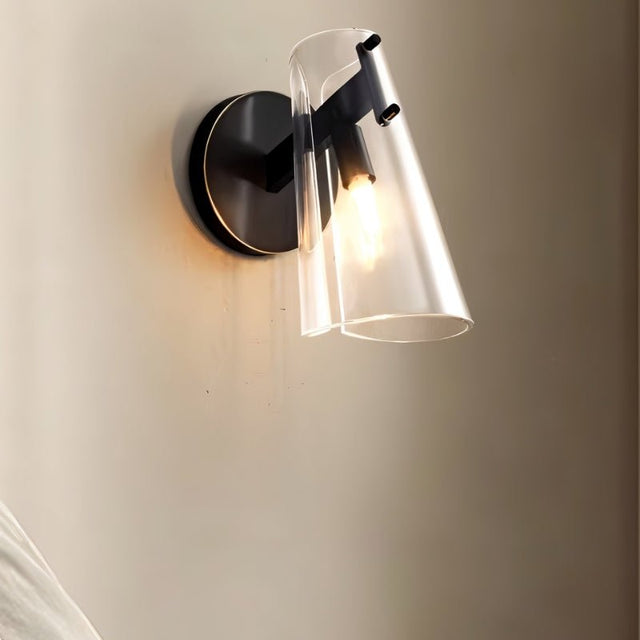 "A modern brass wall lamp with a clear acrylic shade, side view on a neutral wall."