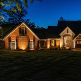 "Outdoor spotlights illuminating a house facade at night, highlighting architectural details."