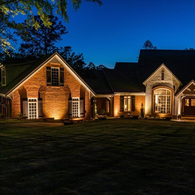"Outdoor spotlights illuminating a house facade at night, highlighting architectural details."