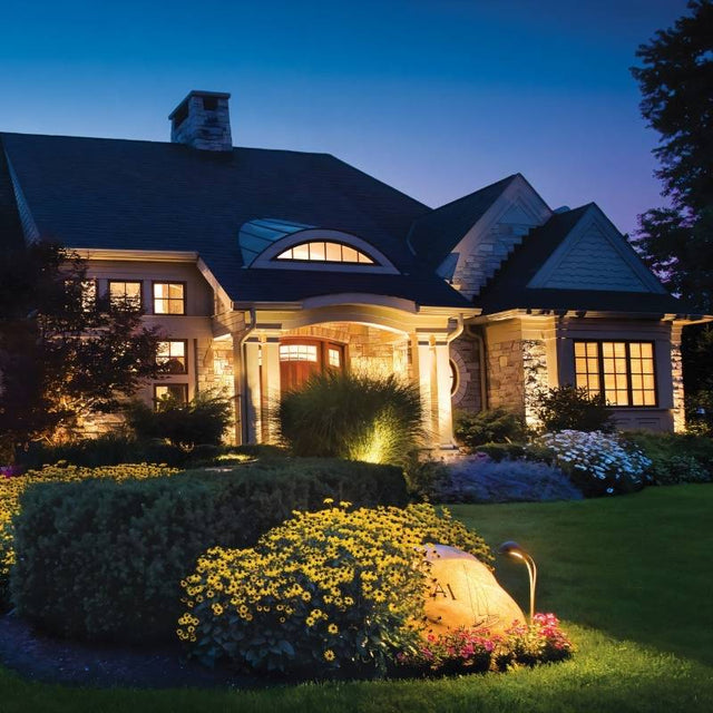 "Outdoor spotlights illuminating a house and garden at night, highlighting architectural and landscape features."