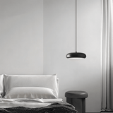 Single Emiva Pendant Light hanging beside a bed, providing soft ambient lighting for a modern bedroom setup.