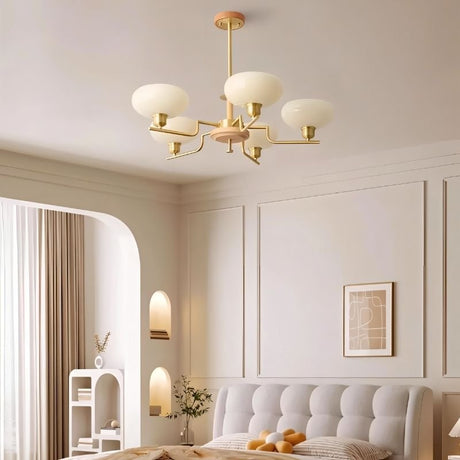 "Brass and wood chandelier with five white globe-shaped glass shades, hanging in a bedroom with panel molding and a plush bed."
