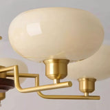 "Close-up of a white globe-shaped glass shade and brass arm of a chandelier."