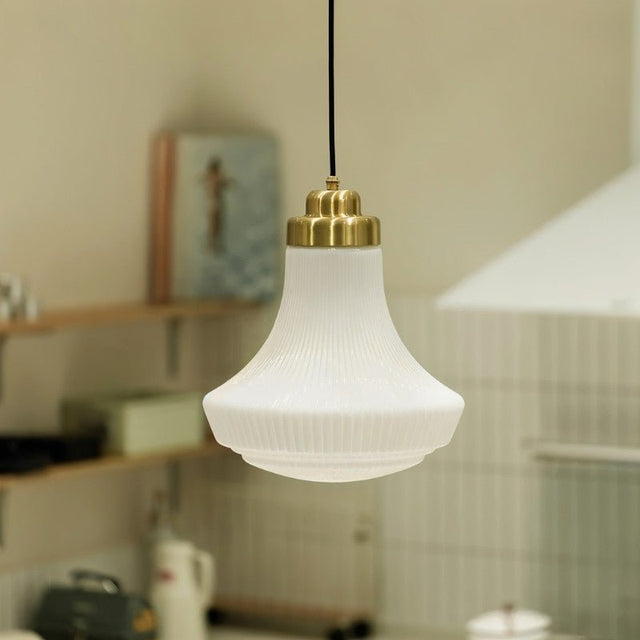 "Retro pendant light with a bell-shaped, striped glass shade and brass hardware illuminating a kitchen, adding vintage-inspired charm with a soft, inviting glow."