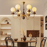 "Gold and dark wood Eurot chandelier with frosted glass globes hanging above a dining table in a traditional dining room."