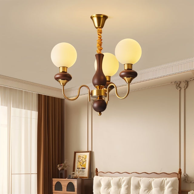 "Gold and dark wood Eurot chandelier with four frosted glass globes hanging in a traditional bedroom."