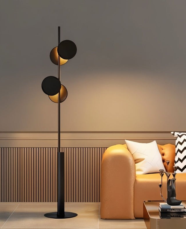 "A modern floor lamp with multiple circular shades, illuminating a living room with a tan sofa and decorative items."
