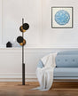 "A modern floor lamp with multiple circular shades, illuminating a living room with a blue sofa and artwork."