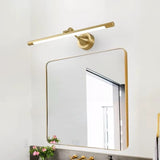 "A sleek gold wall lamp with a horizontal bar design, mounted above a square mirror with rounded corners in a contemporary bathroom setting."