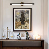 "A sleek black wall lamp with a horizontal bar design, mounted above a framed painting in a contemporary living room, providing focused illumination."