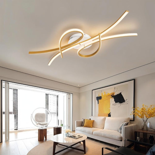 "A modern gold ceiling light with intertwining LED bars in a spacious living room with large windows and contemporary decor."