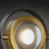 "A close-up view of the Fabli wall lamp showing the glass lens, brass ring, and lit bulb."