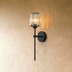 Two wall sconces with pleated cylindrical shades and circular backplates shown in technical dimension drawings on white backg