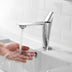 Chrome single-handle bathroom faucet with tall spout over white sink basin with running water.