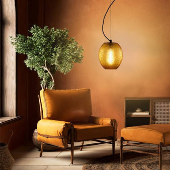 "An amber glass pendant lamp with a textured, organic design hanging in a living room with a leather armchair and a potted plant."