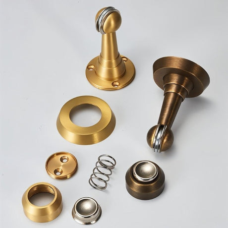 "Exploded view of a magnetic door stop showing its various components in brushed gold and silver finishes."