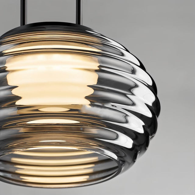 "Close-up of a smoky grey Filano pendant light showing the ribbed glass shade and warm diffused glow."