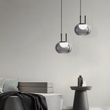 "Two smoky grey Filano pendant lights with ribbed glass shades and iron frames, hanging in a modern interior with a sofa and side table."