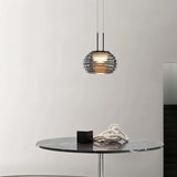 "Smoky grey Filano pendant light with ribbed glass shade and iron frame, hanging above a marble table with decorative objects."