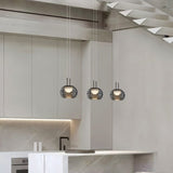 "Three smoky grey Filano pendant lights with ribbed glass shades and iron frames, hanging above a kitchen island."
