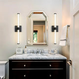 "Modern black wall sconces with clear glass shades flanking a bathroom vanity mirror."