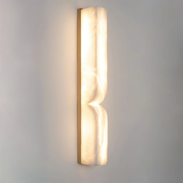 "Close-up of a double curved alabaster wall lamp, showcasing its texture and warm light."