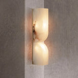 "A double curved alabaster wall lamp illuminating a corner with a soft, diffused light."