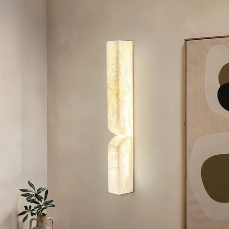 "A double curved alabaster wall lamp illuminating a modern interior with a warm glow."
