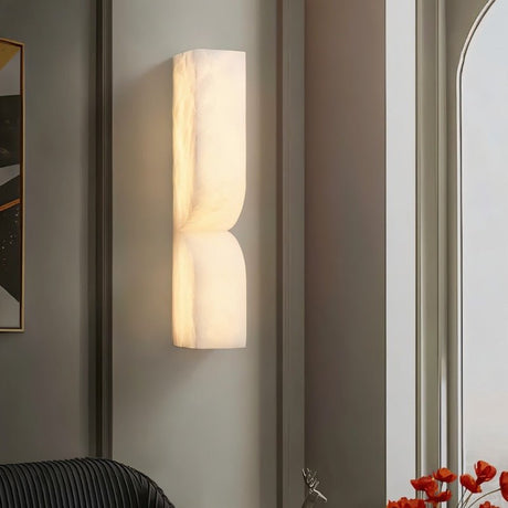 "A double curved alabaster wall lamp enhancing the ambiance of a decorated living room."