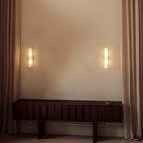 "Two double curved alabaster wall lamps flanking a console in a living room, providing ambient lighting."