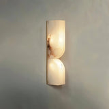 "A double-curved alabaster wall sconce emitting a soft, warm light."