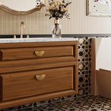 "Vintage brass fan-shaped drawer pulls with a ridged, pleated surface, installed on a wooden bathroom vanity with a white marble countertop, adding a touch of Art Deco elegance to the space."