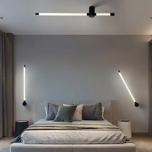 "Modern bedroom with a combination of ceiling and wall lamps featuring long, thin light bars with black finishes and acrylic diffusers, creating a cohesive and well-lit space."