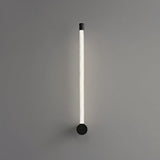 "A sleek, minimalist black wall lamp with a long, thin light bar and acrylic diffuser, mounted vertically on a gray wall."