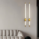 "Two modern wall sconces with long, thin light bars and yellow accent discs, mounted on a light gray wall above a sofa in a living room."