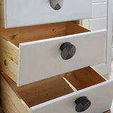 "Dark geometric knobs with etched detailing on white drawers with natural wood interiors."