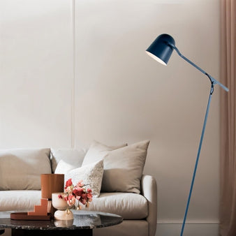 "A blue floor lamp with an adjustable arm and a cone-shaped shade in a modern living room with a gray sofa and a round coffee table."