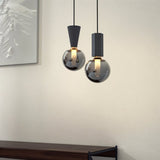 "Modern pendant lights with concrete, metal, and smoky glass orbs, adding a touch of industrial chic to a contemporary bedroom."