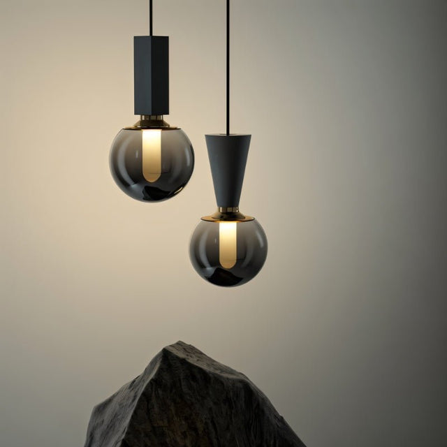"Modern minimalist pendant lights combining concrete, metal, and smoky glass orbs for a sophisticated industrial look."