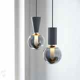 "Modern pendant lights featuring a combination of concrete, metal, and smoky glass orbs, creating a blend of industrial and sophisticated styles."