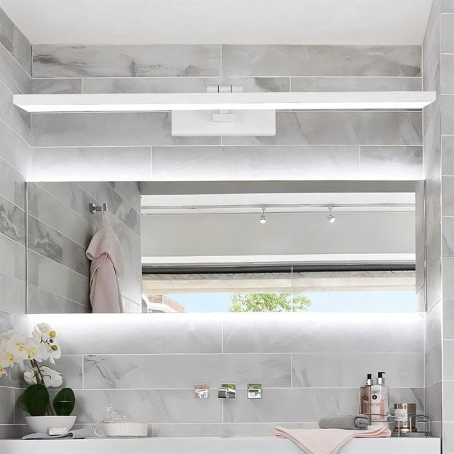 "A white LED vanity light mounted above a large bathroom mirror with a tiled wall."