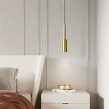 "Minimalist brass pendant light with a slender, cylindrical profile, providing focused downward illumination as a bedside reading light in a modern bedroom."