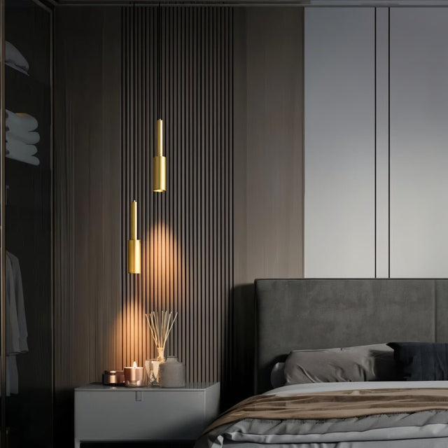 "Sleek, minimalist pendant light with a cylindrical brass or iron body, providing a refined, industrial look ideal for contemporary spaces, casting a focused downward light for accent or task lighting."