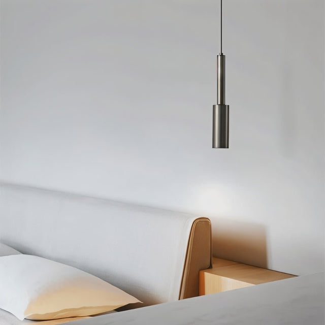 "Minimalist iron pendant light with a slender, cylindrical profile, providing focused downward illumination in a modern bedroom setting."