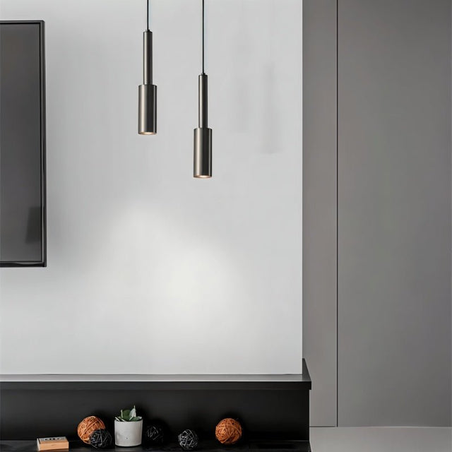 "Pair of minimalist iron pendant lights with slender, cylindrical profiles, adding a refined, industrial touch to a modern living room."