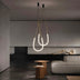 Two teardrop-shaped neon pendant lights with warm white glow suspended in a modern living room with concrete floors and minimalist furnishings.