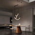 Neon tube chandelier with curved white lights and black hardware suspended above a dining table.
