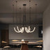 Modern neon tube chandelier with black metal hardware suspended above a wooden dining table in a contemporary interior.